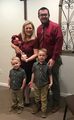 Jacob and Carra Greer standing with their two young sons and baby daughter in the church
